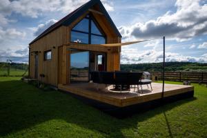 a cabin with a deck with a table and chairs at Stodoła Nad Dadajem in Kojtryny