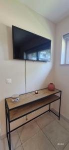 a flat screen tv on a wall with a table at Chambre d'hôte Escale piscine in Ghislenghien