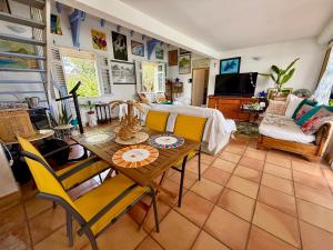 a living room with a table and yellow chairs at VILLA PASKEDRA in Case-Pilote
