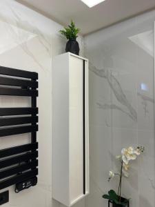 a white bathroom with a mirror and flowers on a shelf at Green House in Vico Equense