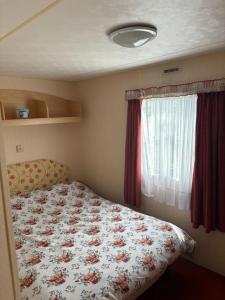 a bedroom with a bed with a floral comforter and a window at Jay Valley Van in Flamborough