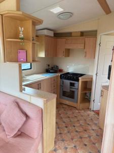 a small kitchen with wooden cabinets and a stove at Jay Valley Van in Flamborough