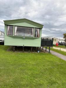 a green tiny house sitting in the grass at Jay Valley Van in Flamborough