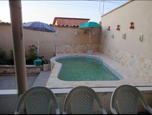 a swimming pool with an umbrella and two umbrellas at Hostel da Lua in Barreirinhas