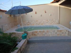 a pool with an umbrella next to a brick wall at Hostel da Lua in Barreirinhas