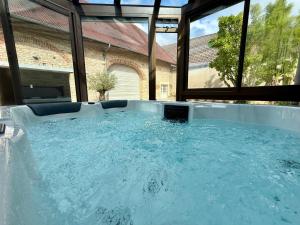 a hot tub in a room with large windows at Le Petit Refuge - La Petite Longère in Rahon