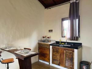 a kitchen with a sink and a table in a room at Chalés do Chá in Lavras Novas