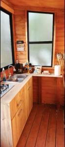 a kitchen with wooden cabinets and a sink and two windows at Silua Eco glamping in Tibasosa