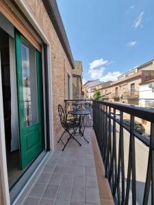 ein Balkon mit Tisch und Stühlen und einer grünen Tür in der Unterkunft Cerere Suite in Biccari