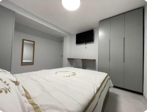 a bedroom with a large white bed and a flat screen tv at בוטיק בהרי הקסטל in Mevasseret Zion