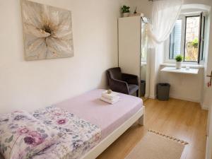 a small bedroom with a bed and a chair at Rooms MADI in Split