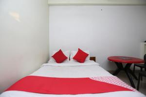 a bedroom with a bed with red pillows and a red table at Hotel O Nandi Inn in Durgāpur +19 photos