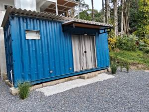 a blue outhouse with a small door in a yard at Flat Container 3 Km do Centro de Brusque para até 4 pessoas in Brusque