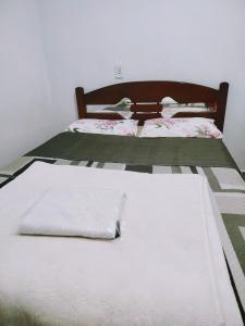 two beds with white sheets and pillows on them at Minha casa pousada in Botucatu +2 photos