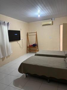 a bedroom with two beds and a flat screen tv at Pousada Amiga in Parintins
