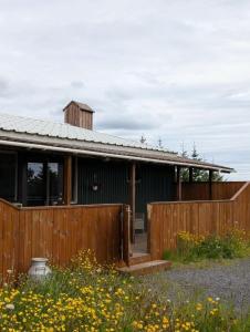 a wooden house with a fence and flowers at Studio apartment in countryside in Selfoss