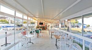 a restaurant with white chairs and tables and windows at Ceti̇n Presti̇ge Resort in Erdek