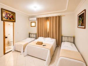 a hotel room with three beds and a bathroom at Hotel Eldorado de Salinas in Salinas