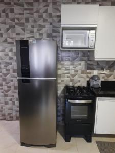 a kitchen with a stainless steel refrigerator and a microwave at Machado Monteiro in Guarapari