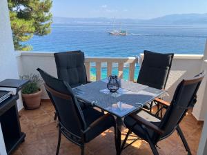 a table and chairs on a balcony with the ocean at Apartment Andrea in Sutivan