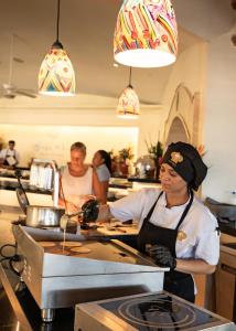 a woman is preparing food in a kitchen at Perla de la Playa Beachfront Hotel in Tamarindo
