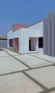 a large white building with a brick wall at Rouge Villa in Winneba