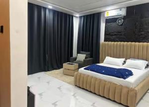 a bedroom with a large bed and a chair at Rouge Villa in Winneba