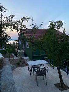 a table and chairs in front of a green house at Pateriku Apartments in Shkodër