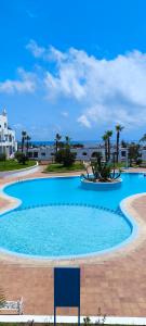 a large blue swimming pool with palm trees and the ocean at kabila vista Z1 2 chambres in M'diq