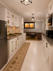 a large kitchen with white cabinets and a living room at Pyramids View Rooftop Apartment in Ghaţāţī