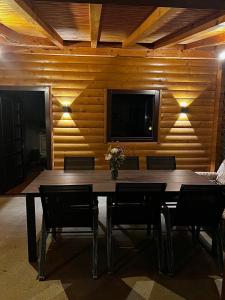 a dining room with a table and chairs and a television at Log Cabin Plavšić - Vikendica Plavšić in Šipovo