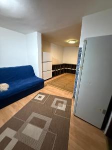a room with a blue couch and a refrigerator at Loret in Kragujevac