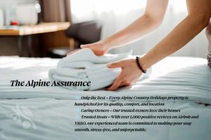 a woman is putting towels on a bed at Alpine Digs in Jindabyne