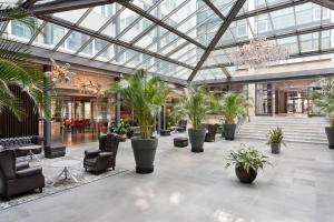 a lobby with palm trees and chairs and a chandelier at Four Points Sheraton Bolzano Bozen in Bolzano