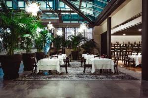 a restaurant with white tables and chairs and plants at Four Points Sheraton Bolzano Bozen in Bolzano