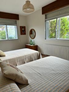 a bedroom with two beds and two windows at Casiña Carreiro in Beade