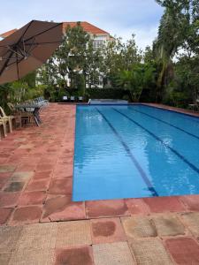 a swimming pool with an umbrella and tables and chairs at Bubuli country club in Lyamutundwe