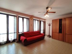 a living room with a red couch and windows at Will House in Lanzo Torinese