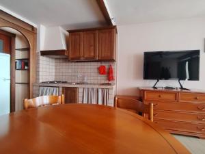 a kitchen with a wooden table with chairs and a television at Will House in Lanzo Torinese