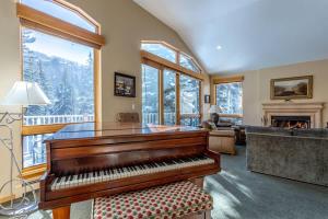 a living room with a piano and a fireplace at Gore Creek Alpine Chalet in Vail