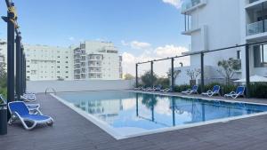 a swimming pool with lounge chairs next to a building at Elegant 2BR Jade Serenity - Masdar City Retreat in Al Qurayyah