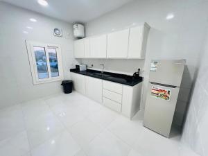 a white kitchen with white cabinets and a refrigerator at فـيليج سـانـسـت Village Sunset in Al Namas