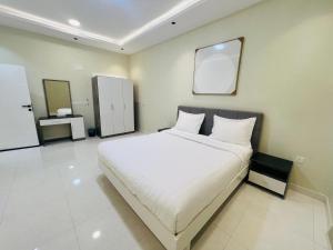 a bedroom with a white bed and a mirror at فـيليج سـانـسـت Village Sunset in Al Namas