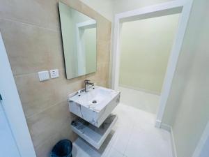 a bathroom with a white sink and a mirror at فـيليج سـانـسـت Village Sunset in Al Namas