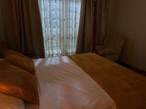 a bedroom with a bed and a chair and a window at Bubuli country club in Lyamutundwe