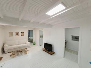 a white living room with a couch and a tv at A Casiña do Río in Celanova
