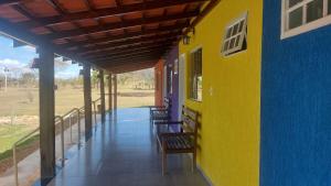 a porch of a house with a yellow and blue wall at Cachoeiras Pé da Serra in São João Batista do Glória