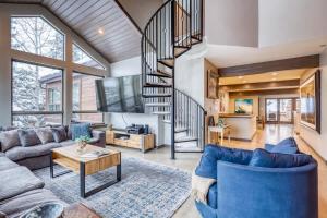 a living room with a spiral staircase and blue couches at Vail Ski-In Ski-Out Chalet in Vail