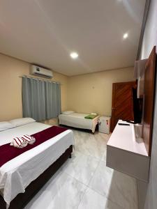 a hotel room with two beds and a sink at Pousada Mineira in Barreirinhas