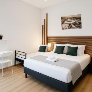 a bedroom with two beds and a table and a desk at Kariokas Hospedagem in Águeda